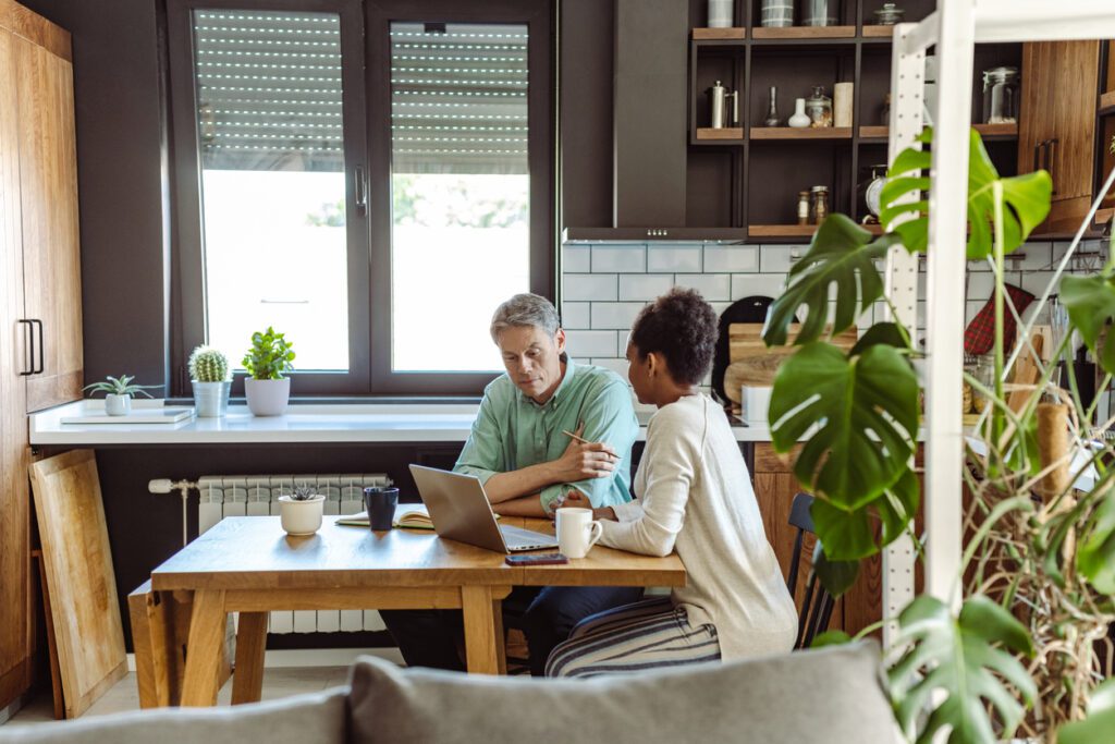 Multi-racial mature couple calculating costs at home at the table. They discussing home finances