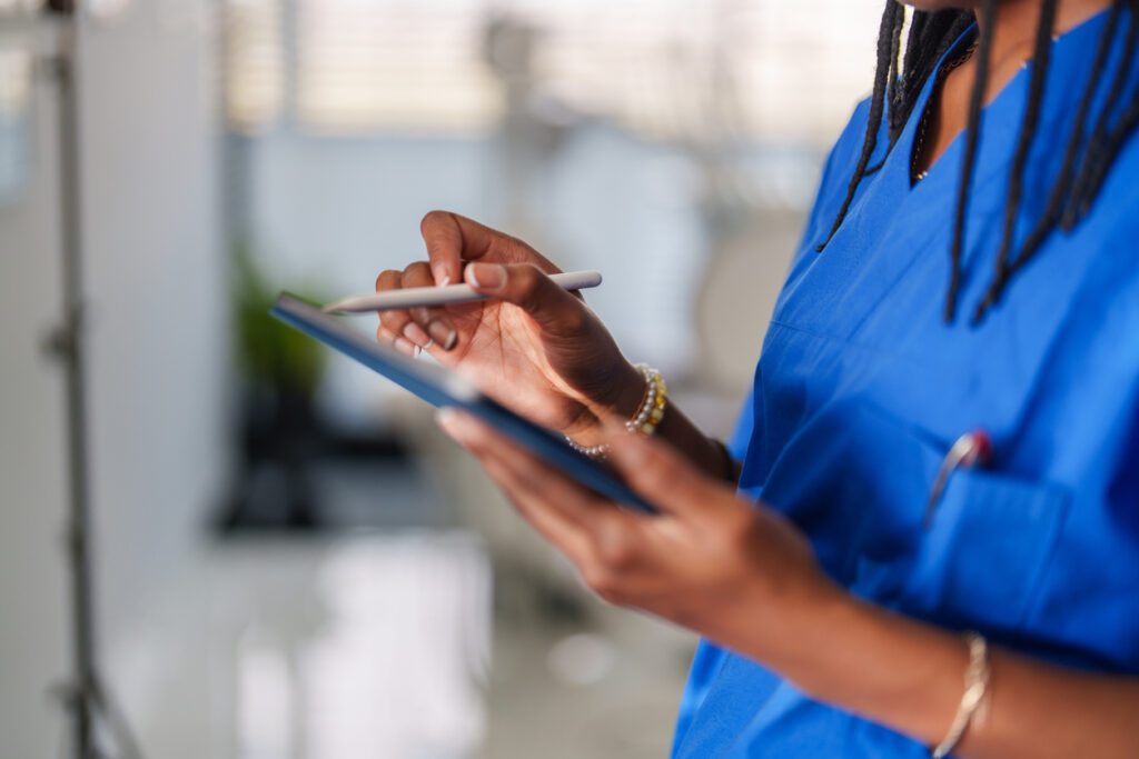 African Ethnicity female healthcare worker with blue scrubs working in medical clinic.