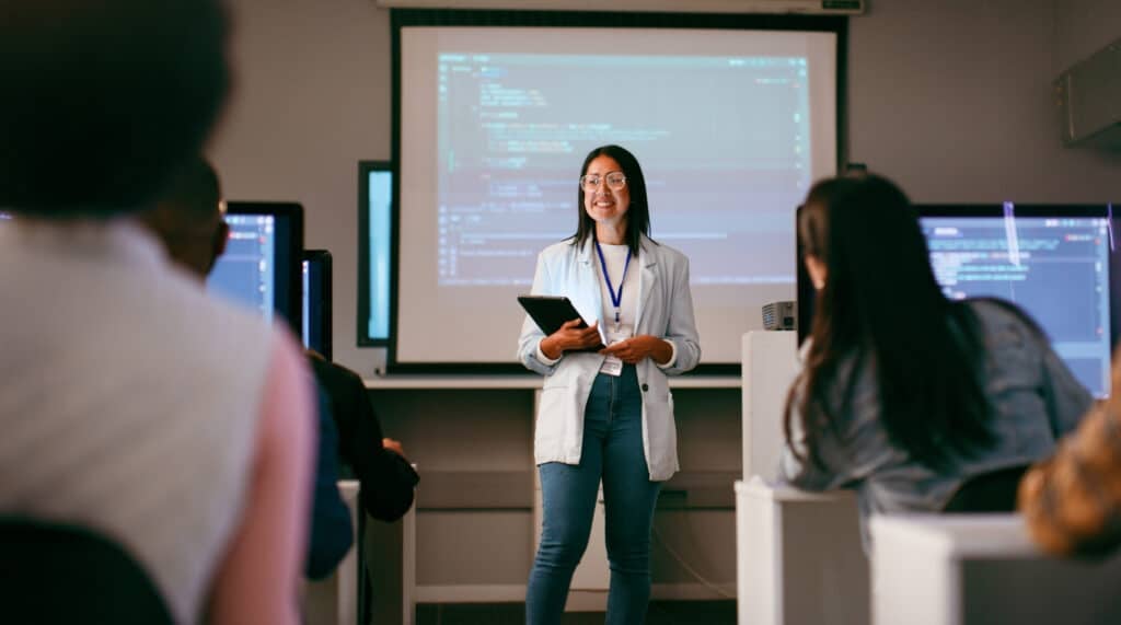 A dynamic scene showing a diverse group of students attending a coding lecture. The instructor, using digital tools, leads the session in a modern classroom setting, fostering an inclusive and collaborative learning environment.