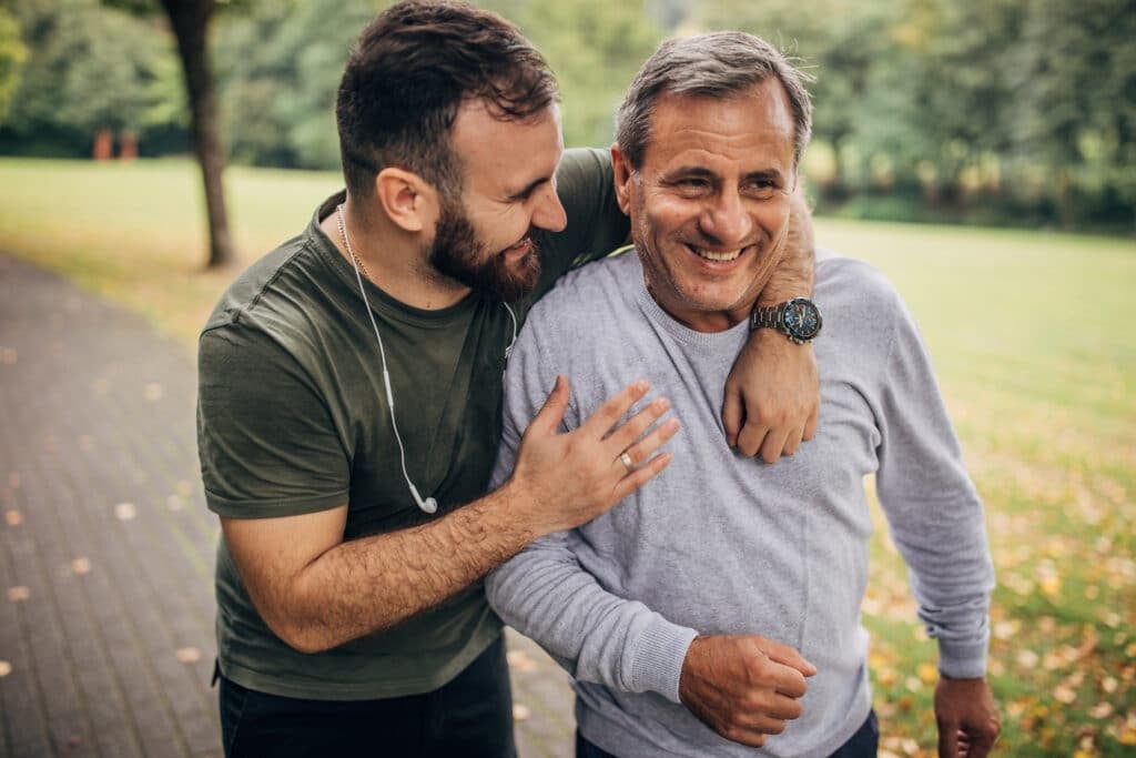 Senior father and adult son jogging in park