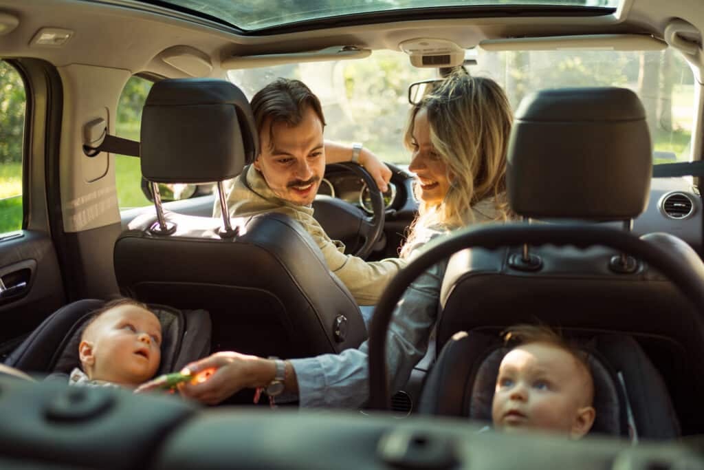 A happy family with twin babies gets ready to start their road trip