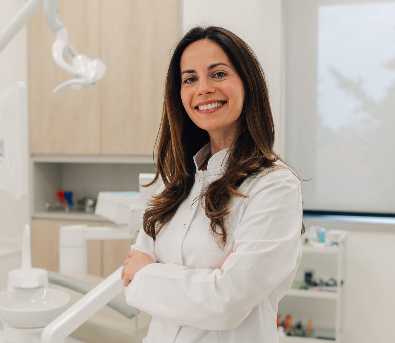 Confident female dentist smiling with arms crossed in her modern dental clinic